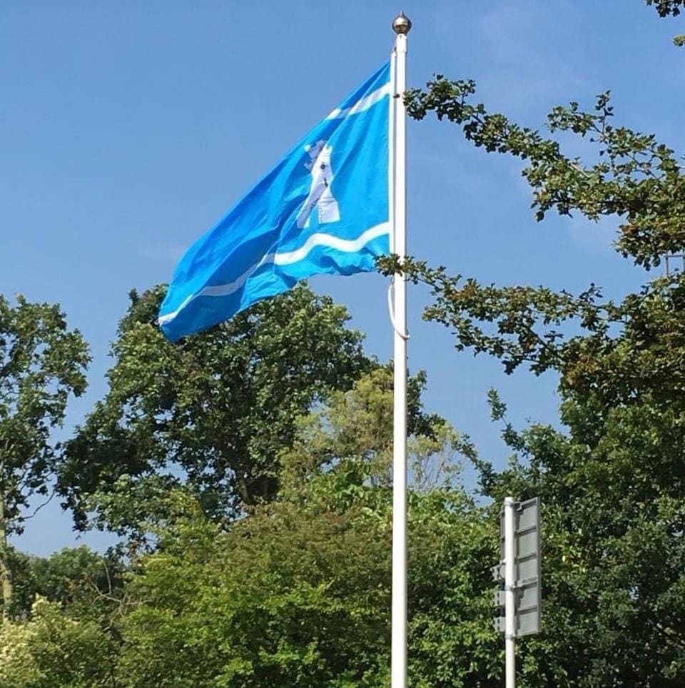 De Domburgse vlag wappert aan een vlaggenmast tegen een blauwe lucht