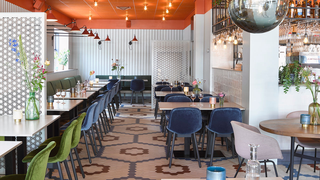 Blik door het restaurant met blauwe fluwelen stoelen en de gekleurde tegelvloer