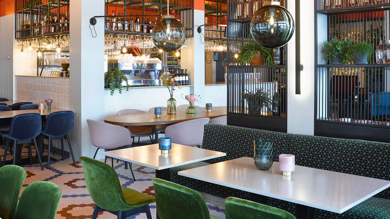 Het interieur van Markt Zes met groene banken, de bar en de gekleurde tegelvloer