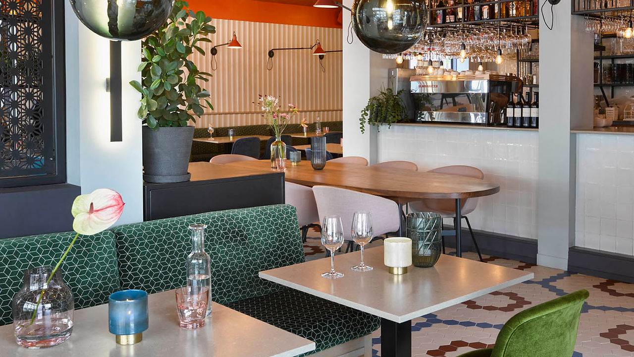 Tafels met groene banken en fluwelen stoelen in het restaurant