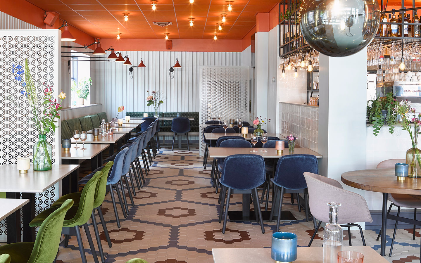 Het restaurant van Markt Zes met blauwe en olijfgroene stoelen, een koraalrood plafond en een hexagonale tegelvloer