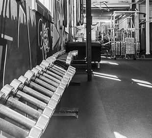 Rij dumbbells langs de graffitimuur in de sportruimte