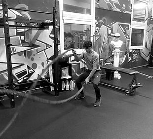 Sporter traint met battle ropes tijdens een groepstraining